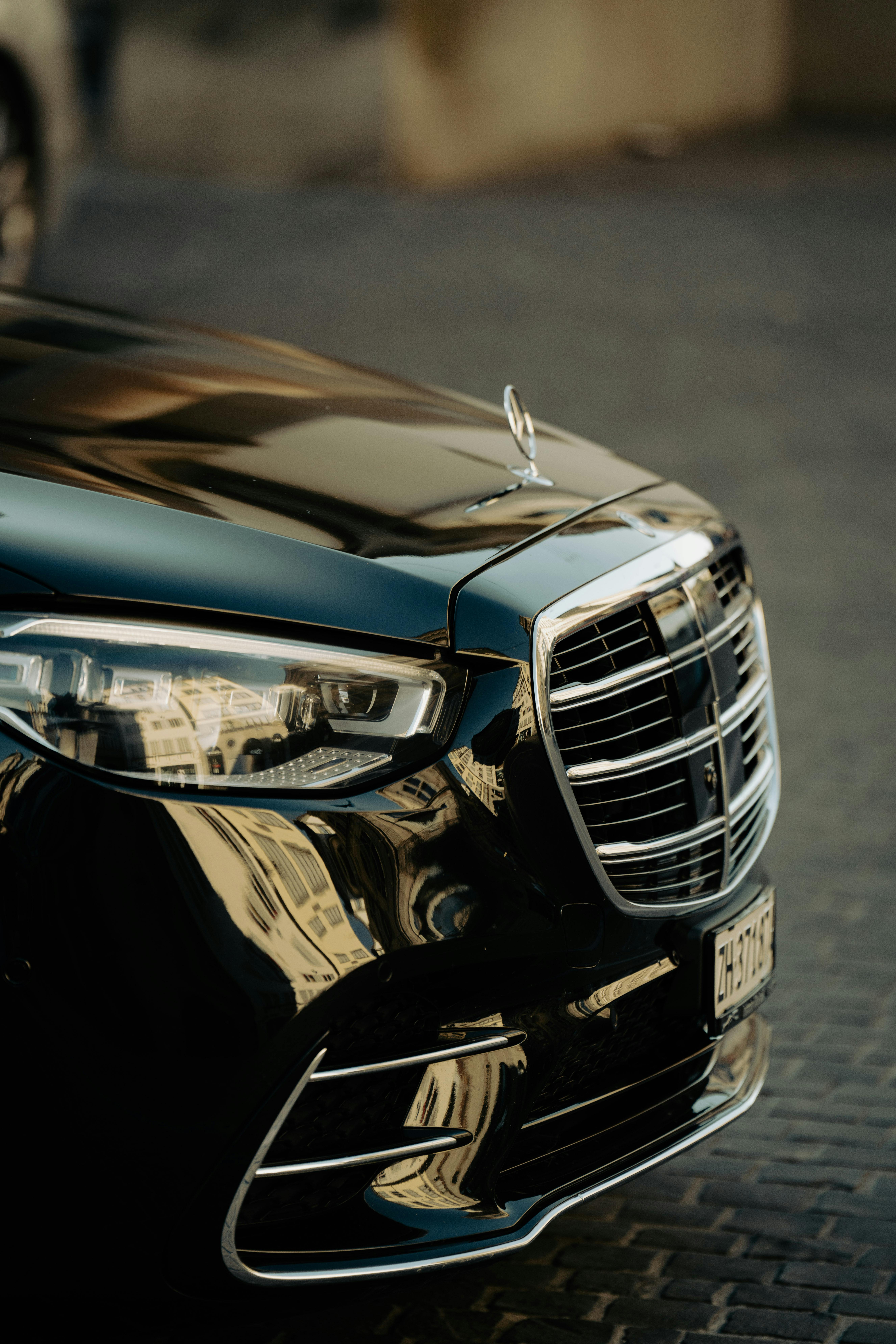 Close-up of a luxury black car's front showcasing its sleek design and reflective finish.